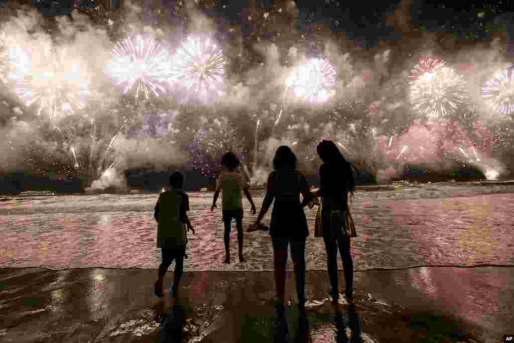 People celebrate the start of the New Year as fireworks illuminate Copacabana Beach in Rio de Janeiro, Brazil, Jan. 1, 2024.