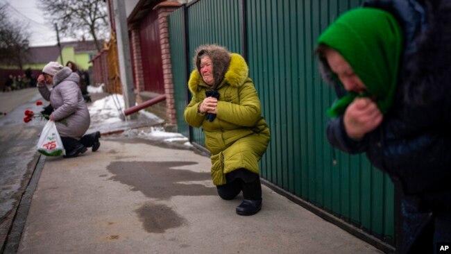 Njerëzit gjunjëzohen ndërsa kthehet me arkivol trupi i Oleksandr Maksymenko, 38 vjeç, vullnetar në forcat ukrainase (Kniazhychi, Ukrainë, 13 shkurt 2023)