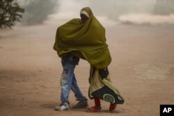 Somali refugee children cover as a dust storm moves across the Dadaab refugee camp in northern Kenya, July 13, 2023.