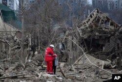 Seorang pekerja medis menghibur seorang perempuan di lokasi serangan udara Rusia, di Zaporizhzhia, Ukraina, 22 Maret 2024. (Foto: AP)