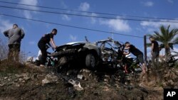 Palestinians gather around a car destroyed in a drone strike Zeita village, north of the West Bank city of Tulkarem, Aug. 3, 2024.