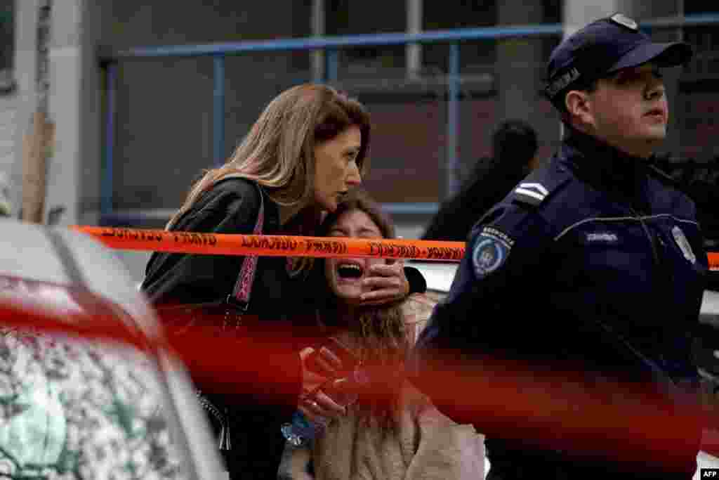 A parent walks with her child following a deadly shooting at an elementary school in Belgrade, Serbia.