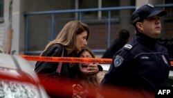 A parent escorts her child following a deadly shooting at an elementary school in Belgrade, Serbia.