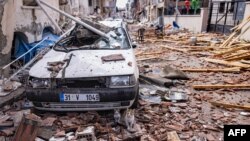 Cats sit in rubble front of a destroyed car at a damaged street after a 6.4-magnitude quake hit the Hatay province in southern Turkey, in Antakya, Feb. 21, 2023.