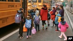 Migrant children prepare to board a school bus while guided by their guardians in front of the Row Hotel that serves as a migrant shelter on Dec. 12, 2023, in New York.