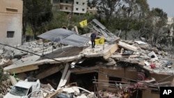 Seorang pria tampak berdiri di atas reruntuhan rumah yang hancur akibat serangan Israel di desa Hanine, di selatan Lebanon, pada 25 April 2024. (Foto: AP/Mohammed Zaatari)