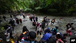 FILE - Migrants, mostly Venezuelans, cross a river during their journey through the Darien Gap from Colombia into Panama, hoping to reach the US, Oct. 15, 2022. 