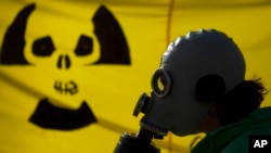 FILE - A man with a gas mask protests near the chancellery against nuclear power in Berlin, March 26, 2011.