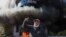 A demonstrator gestures near a bank, set on fire, during a protest against informal restrictions on cash withdrawals and deteriorating economic conditions in Beirut, Lebanon, Feb. 16, 2023.