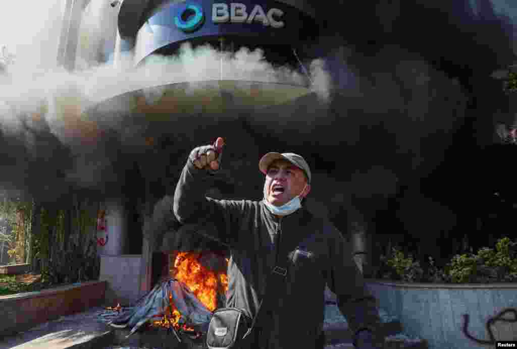 A demonstrator gestures outside a bank set on fire during a protest against informal restrictions on cash withdrawals and deteriorating economic conditions in Beirut, Lebanon.