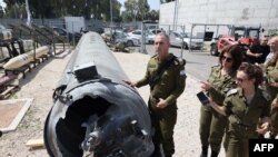 Портпаролот на израелската војска Даниел Хагари и други членови на израелската војска стојат покрај иранската балистичка ракета која падна во Израел викендов, за време на медиумската посета на воената база Јулис, 16 април 2024 година
