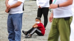 Un niño se sienta en medio de excombatientes de las FARC para una ceremonia en la que exrebeldes se disculparon con los lugareños por los secuestros llevados a cabo por las FARC durante décadas en la zona rural de Pipiral cerca de Villavicencio, Colombia, 29 de octubre de 2020.