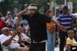 A man dances as JSWISS performs in the Harlem neighborhood of New York, Thursday, Aug. 15, 2024. (AP Photo/Pamela Smith)