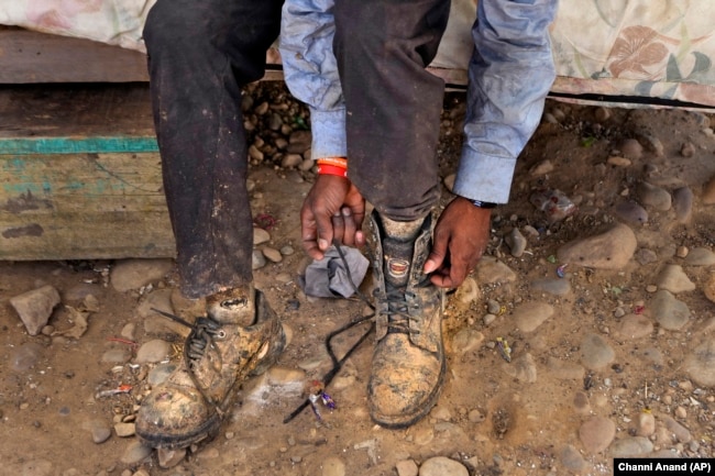 Aamir Shekh puts shoes on before going to work as a waste picker during a heat wave at a garbage dump on the outskirts of Jammu, India, Wednesday, June 19, 2024. (AP Photo/Channi Anand)