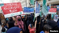 FILE - Women along with their children carry placards as they take part in a protest against price hikes in Karachi, Pakistan, Feb. 15, 2023.