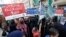 FILE - Women along with their children carry placards as they take part in a protest against price hikes in Karachi, Pakistan, Feb. 15, 2023.