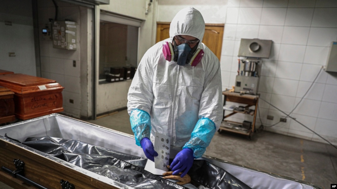 FILE - An employee takes the fingerprints of a coronavirus victim prior to her cremation in Santiago, Chile, June 27, 2020. Countries are still struggling to devise a plan for how the world might respond to the next global outbreak.