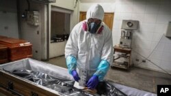 FILE - An employee takes the fingerprints of a coronavirus victim prior to her cremation in Santiago, Chile, June 27, 2020. Countries are still struggling to devise a plan for how the world might respond to the next global outbreak.