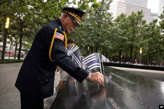 Sam Pulia coloca banderas antes de la ceremonia de conmemoración de los ataques terroristas del 11 de septiembre de 2001, el lunes 11 de septiembre de 2023, en Nueva York.