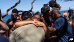Residents of Lahaina, Hawaii, hug one another after a news conference in Lahaina, Aug. 18, 2023.