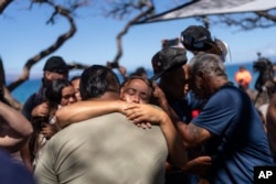 Lahaina residents, who are affected by a deadly wildfire that devastated the community, hug one another after a news conference in Lahaina, Hawaii, Aug. 18, 2023.