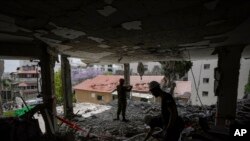 Soldados israelíes y trabajadores municipales inspeccionan los daños a un edificio de apartamentos un día después de que fuera alcanzado por un cohete disparado desde la Franja de Gaza, en Rehovot, Israel.