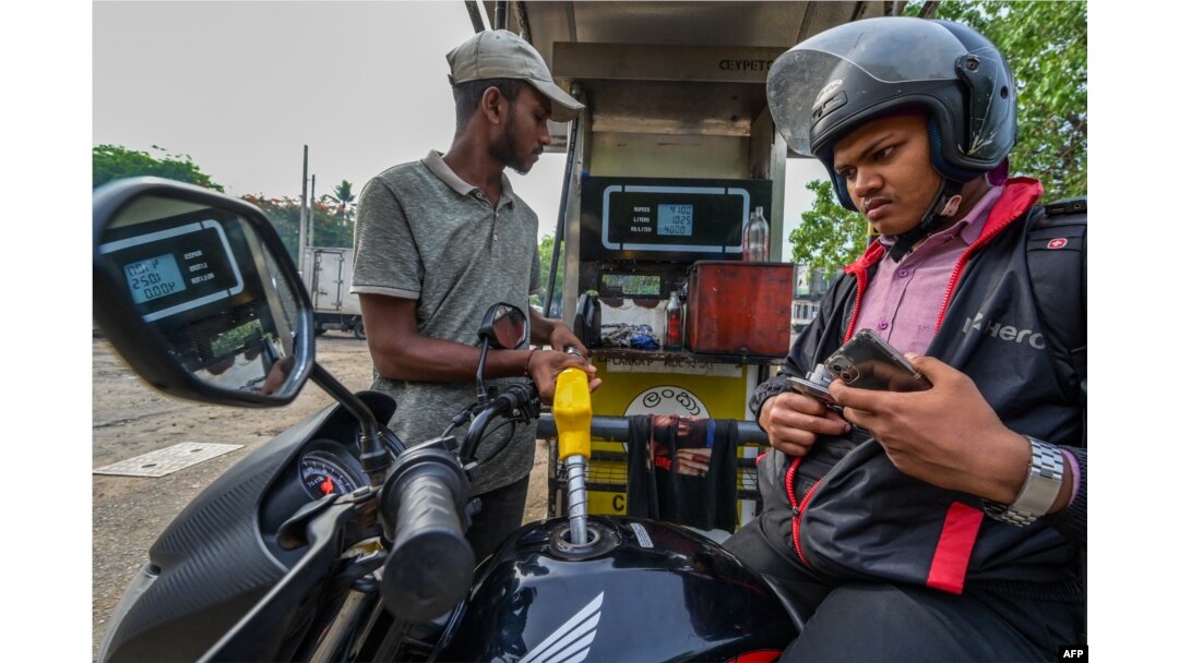 Seorang petugas pom bensin di Sri Lanka, mengisi BBM sepeda motor pelanggannya, 21 Maret 2023. .(ISHARA S.KODIKARA/AFP)