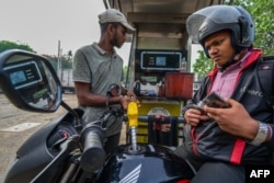 Seorang petugas pom bensin di Sri Lanka, mengisi BBM sepeda motor pelanggannya, 21 Maret 2023. .(ISHARA S.KODIKARA/AFP)