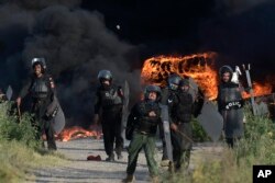 Polisi melempar batu ke arah pendukung mantan perdana menteri Pakistan Imran Khan saat bentrokan, di Islamabad, Pakistan, 10 Mei 2023. (Foto: AP)