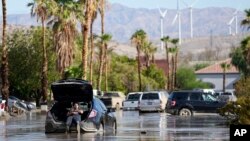 Dorian Padilla sits in his car as he waits for a tow after it got stuck in the mud on a street on Aug. 21, 2023, in Cathedral City, Calif. Forecasters said Tropical Storm Hilary was the first tropical storm to hit Southern California in 84 years.