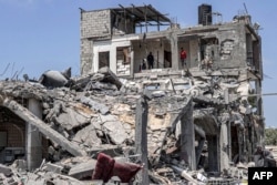Warga memeriksa bangunan yang hancur akibat serangan udara Israel di sisi timur kamp pengungsi Palestina "Maghazi" di Jalur Gaza, 15 April 2024.