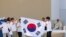 Young pilgrims from South Korea celebrate with their national flag and with Pope Francis after he announced that the next World Youth Day, will be in Seoul, South Korea in 2027, at the end of a mass at Parque Tejo in Lisbon, Aug. 6, 2023. 