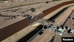 Migrantes hacen fila en la frontera entre Estados Unidos y México antes de abordar un autobús de la Patrulla Fronteriza y Aduanas de EEUU cerca de El Paso, Texas, el 11 de mayo de 2023.
