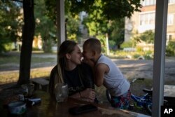 Valeria Pototska cuddles her 5-year-old son David outside their house in Kupiansk-Vuzlovyi, Ukraine, Aug. 23, 2023.