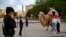 FILE - Tourists pose for photos with a camel outside the Id Kah Mosque in Kashgar in western China's Xinjiang Uyghur Autonomous Region, as seen during a government organized trip for foreign journalists, on April 19, 2021.