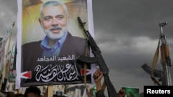 Para pengunjuk rasa, sebagian besar pendukung Houthi, memegang senjata api di samping poster pemimpin Hamas yang dibunuh, Ismail Haniyeh, dalam aksi solidaritas dterhadap warga Palestina di Jalur Gaza, di Sanaa, Yaman, 2 Agustus 2024. (Foto: Khaled Abdullah/Reuters)