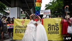 FILE - A same-sex couple poses in wedding dresses as members of the LGBTQ community take part in a Pride March in Bangkok on June 5, 2022. 