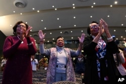 Parishioners clap and raise their hands as Rev. Gina Stewart preaches during church service at Rankin Chapel, April 7, 2024, in Washington.