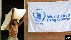 FILE - A woman carries a bag of maize at an aid center in Chikwawa, Malawi, Jan. 17, 2015. Malawi's government last month banned the import of unmilled maize from Kenya and Tanzania, citing concerns about the spread of maize lethal necrosis disease.