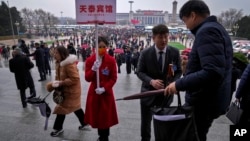 资料照片: 全国人大会议开幕式结束后，北京天泰宾馆工作人员举牌接人大代表回宾馆（2024年3月5日）