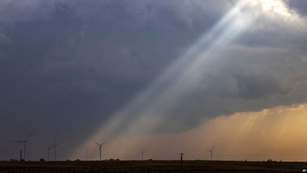 Sunlight filters through storm clouds onto a wind turbine as severe weather rolls through the midwest on Apr. 4, 2023, south of Stuart, Iowa.