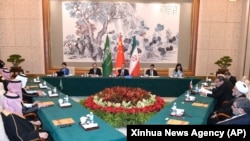 In this photo released by Xinhua News Agency, Wang Yi, China's most senior diplomat, center, presides over a closed meeting between leaders from Iran and Saudi Arabia in Beijing, March 11, 2023.