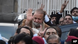 Pakistan's former Prime Minister Nawaz Sharif, center in brown coat, waves to his supporters as he leaves after a court hearing in Islamabad, Pakistan, Dec. 12, 2023. 