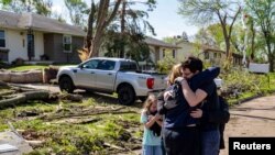 FILE - Neighbors embrace Penny Thomsen outside of her home after tornadoes hit the evening before, Des Moines suburb of Pleasant Hill, Iowa, Apr. 27, 2024. In Oklahoma, 2 people were killed in tornadoes. (Zach Boyden-Holmes/The Register/USA Today Network via Reuters)