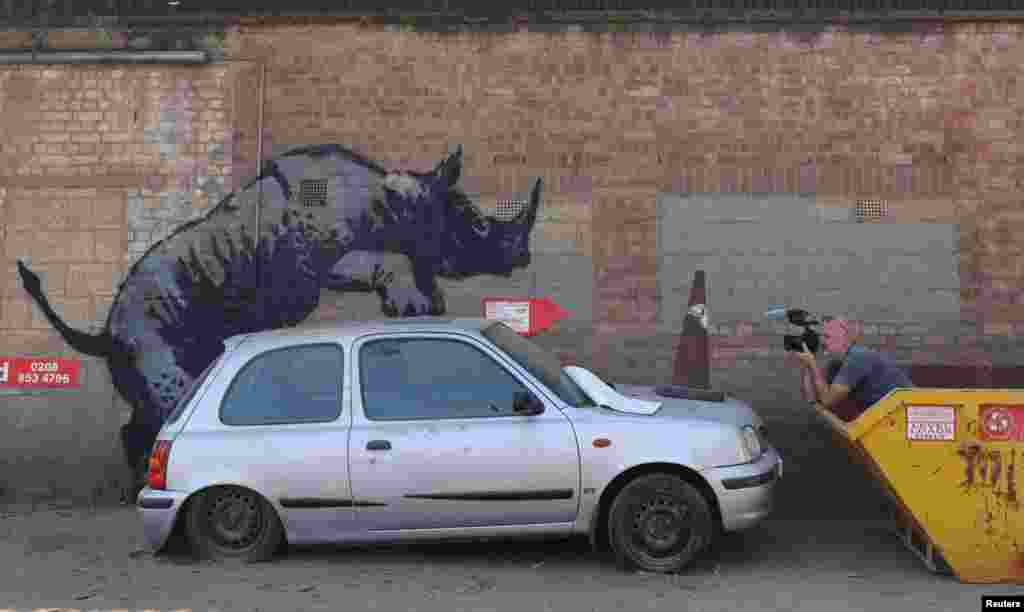 A person takes a photo of a new artwork by the British artist Banksy in Charlton, London, Britain.