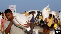 Pengungsi Yaman menerima karung bantuan makanan di sebuah kamp di distrik Hays di provinsi barat Hodeidah yang dilanda perang, 20 April 2023. (Khaled Ziad / AFP)