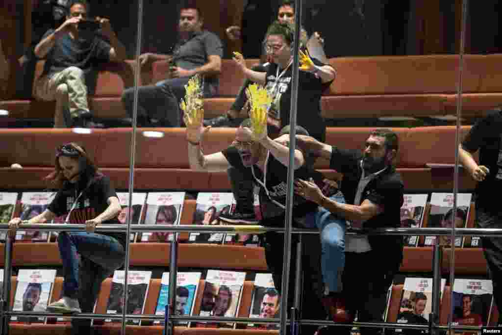 Families and supporters of hostages, kidnapped during the deadly October 7 attack on Israel by Palestinian Islamist group Hamas, smear yellow paint on glass during a demonstration at the Knesset, Israel&#39;s parliament in Jerusalem.