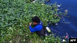A man collects trash during a clean-up along a river in Paranaque City, Metro Manila, Philippines.