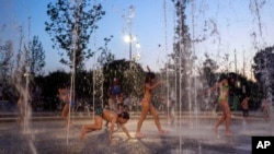 FILE - Children cool off as they play on a fountain at Stavros Niarchos Foundation Cultural Center, in Athens, Greece, July 18, 2024. (AP Photo/Petros Giannakouris)