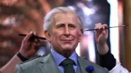 Employees put the final touches on the wax effigy of Britain King Charles III before its unveiling at the Musee Grevin in Paris.